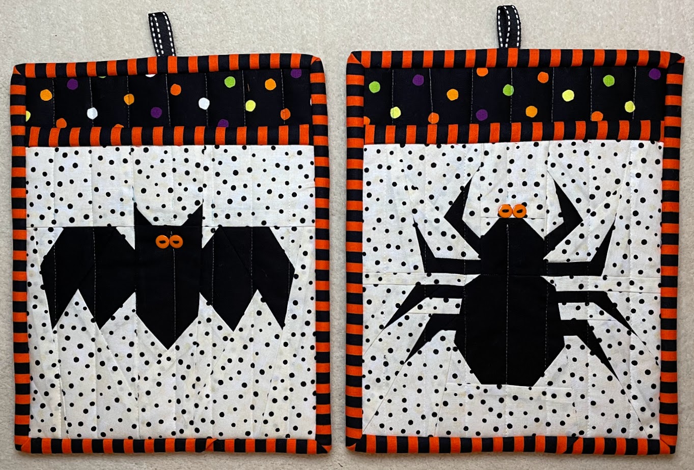 Two potholders, one with a bat, the other with a spider.